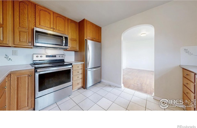 595 E Kiser Ave, Keenesburg, CO 80643 - kitchen with appliances with stainless steel finishes, arched walkways, light countertops, and brown cabinets