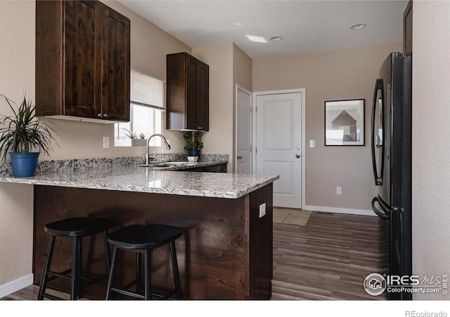 184 S 2nd Ave, Deer Trail, CO 80105 - kitchen featuring freestanding refrigerator, dark brown cabinetry, wood finished floors, a peninsula, and a kitchen bar