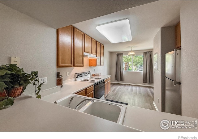 51 21st Ave Unit 43, Longmont, CO 80501 - kitchen featuring white range with electric stovetop, freestanding refrigerator, under cabinet range hood, brown cabinetry, and light wood-style flooring