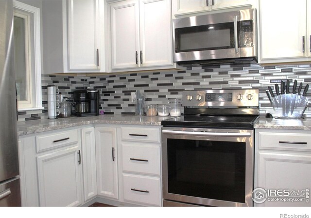 308 Prospect St, Fort Morgan, CO 80701 - kitchen with appliances with stainless steel finishes, white cabinets, decorative backsplash, and light stone counters
