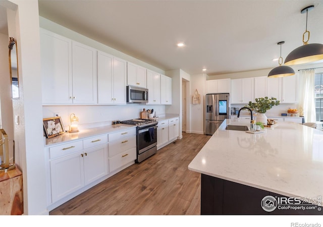 4918 Preserve Pl, Firestone, CO 80504 - kitchen with appliances with stainless steel finishes, light wood finished floors, white cabinets, recessed lighting, and decorative light fixtures