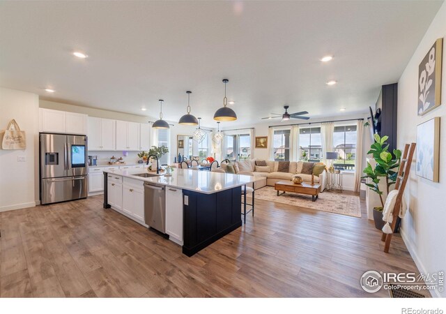 4918 Preserve Pl, Firestone, CO 80504 - kitchen with appliances with stainless steel finishes, light wood-type flooring, white cabinets, open floor plan, and plenty of natural light
