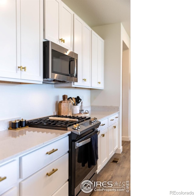 4918 Preserve Pl, Firestone, CO 80504 - kitchen featuring stainless steel appliances, white cabinets, light wood finished floors, and light stone countertops