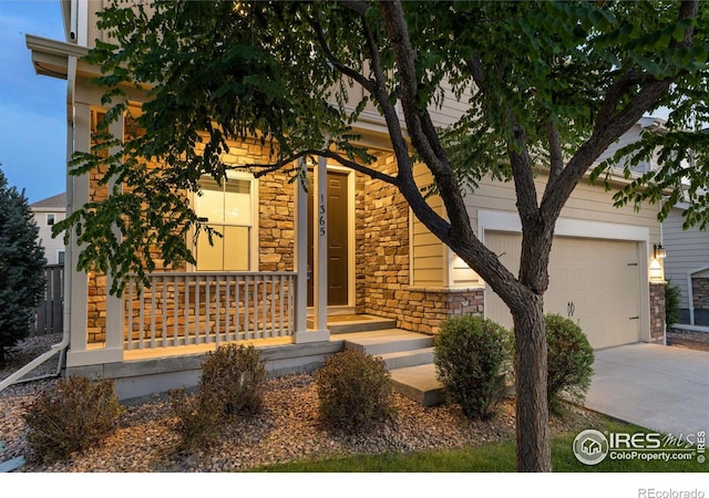 1365 15th Ave, Longmont, CO 80501 - view of property hidden behind natural elements with stone siding, concrete driveway, and covered porch