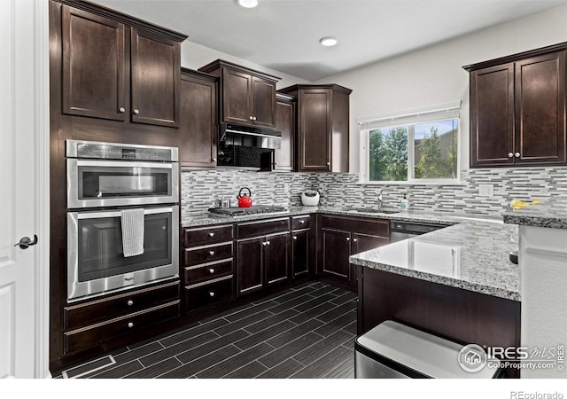 1365 15th Ave, Longmont, CO 80501 - kitchen featuring stainless steel appliances, light stone countertops, backsplash, dark brown cabinetry, and recessed lighting