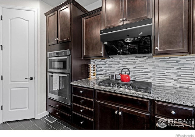 1365 15th Ave, Longmont, CO 80501 - kitchen featuring stainless steel appliances, tasteful backsplash, light stone countertops, dark brown cabinetry, and dark tile patterned floors