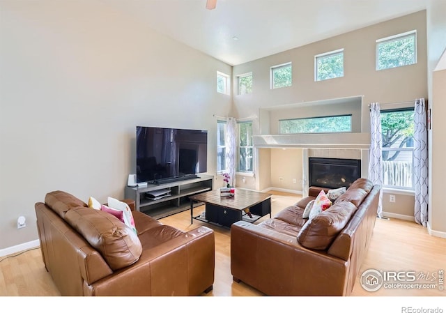 1747 Daisy Ct, Brighton, CO 80601 - living room featuring light wood-style floors, a high ceiling, plenty of natural light, and a glass covered fireplace