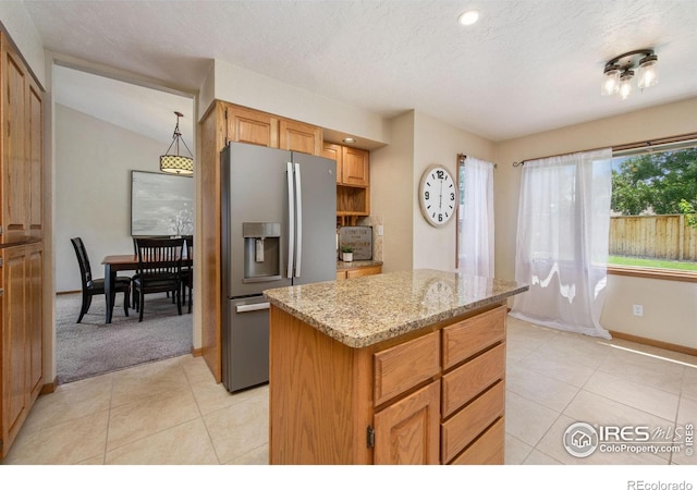 904 Pine Dr, Windsor, CO 80550 - kitchen with stainless steel fridge, light tile patterned flooring, a kitchen island, light stone counters, and a textured ceiling