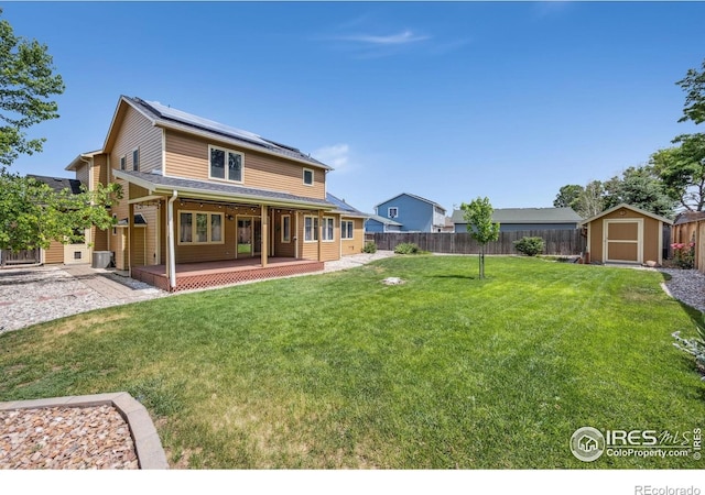 904 Pine Dr, Windsor, CO 80550 - back of house with a shed, roof mounted solar panels, a fenced backyard, and covered porch