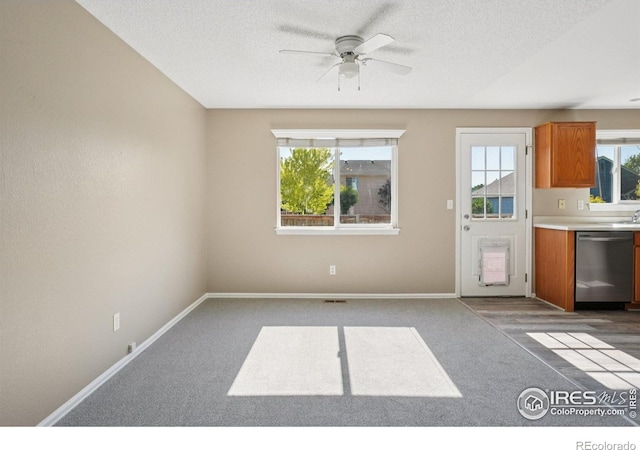 1506 Crestwood Cir, Longmont, CO 80504 - kitchen with stainless steel dishwasher, ceiling fan, brown cabinetry, carpet, and a textured ceiling