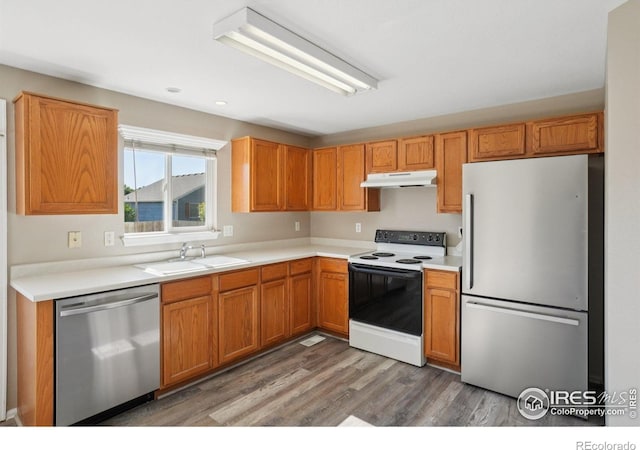 1506 Crestwood Cir, Longmont, CO 80504 - kitchen featuring appliances with stainless steel finishes, under cabinet range hood, light wood-style floors, light countertops, and brown cabinetry