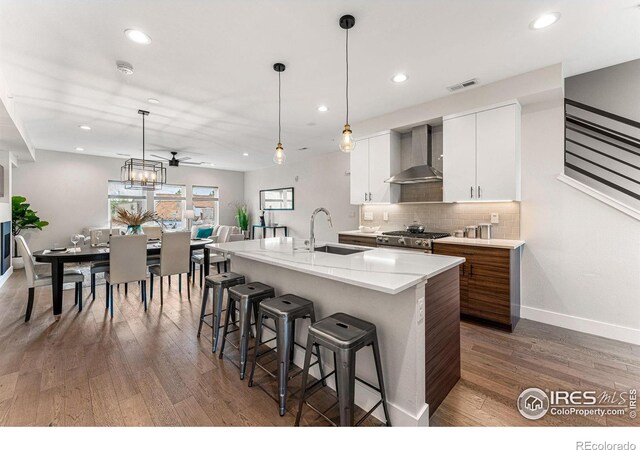 3450 N Downing St Unit 4, Denver, CO 80205 - kitchen with wall chimney exhaust hood, recessed lighting, wood finished floors, a breakfast bar, and tasteful backsplash