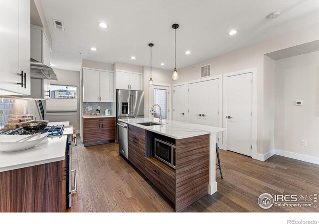 3450 N Downing St Unit 4, Denver, CO 80205 - kitchen featuring appliances with stainless steel finishes, wood finished floors, a kitchen breakfast bar, tasteful backsplash, and recessed lighting