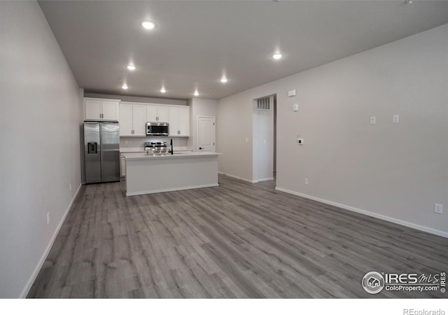 2714 Barnstormer St Unit G, Fort Collins, CO 80524 - kitchen featuring stainless steel appliances, recessed lighting, wood finished floors, a center island with sink, and white cabinets