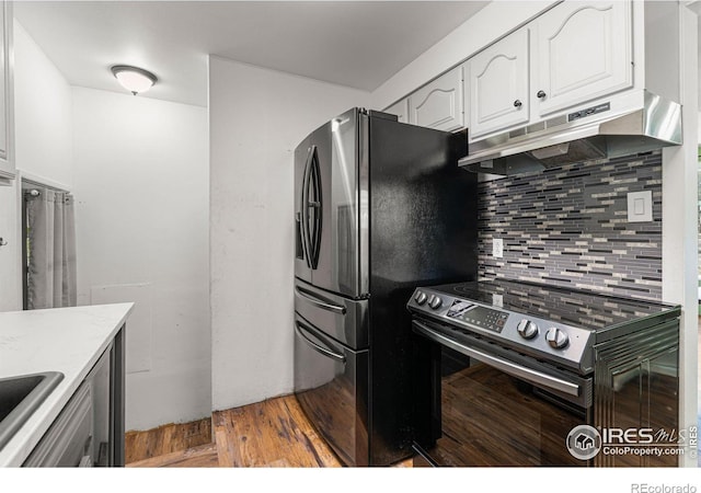 1109 Ironton St, Aurora, CO 80010 - kitchen with electric range, under cabinet range hood, freestanding refrigerator, white cabinetry, and decorative backsplash