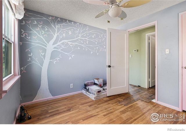 1109 Ironton St, Aurora, CO 80010 - spare room with wood finished floors, ceiling fan, healthy amount of natural light, wallpapered walls, and a textured ceiling