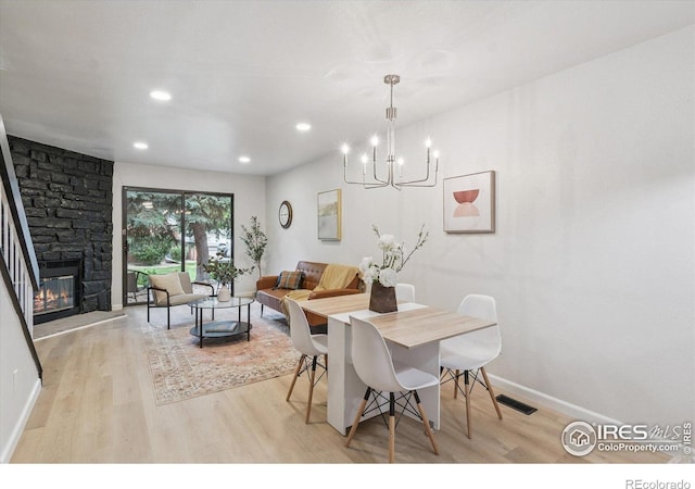 7474 E Arkansas Ave Unit 12, Denver, CO 80231 - dining room featuring light wood-type flooring, a chandelier, a stone fireplace, and recessed lighting