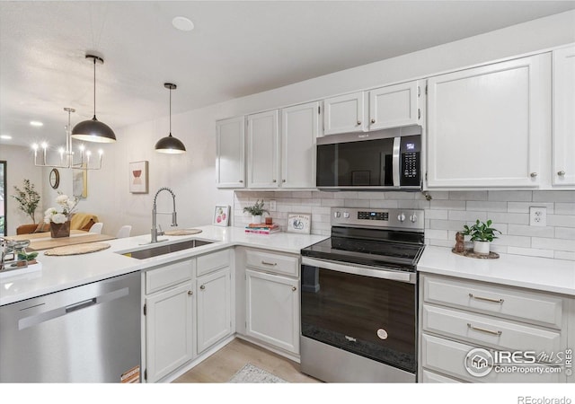 7474 E Arkansas Ave Unit 12, Denver, CO 80231 - kitchen with appliances with stainless steel finishes, decorative backsplash, light countertops, white cabinets, and hanging light fixtures