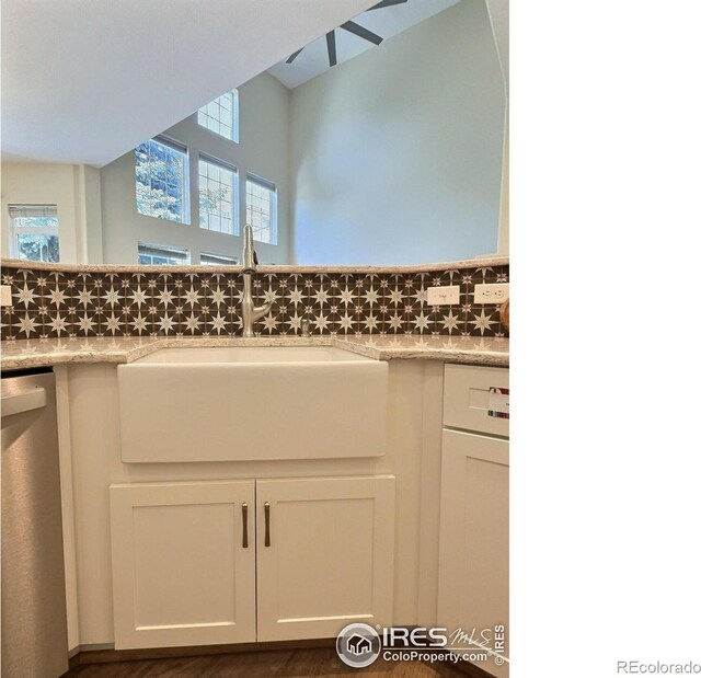3000 E 112th Ave Unit 102, Northglenn, CO 80233 - detailed view of dishwasher, white cabinets, backsplash, and light stone countertops