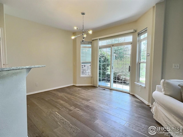 3000 E 112th Ave Unit 102, Northglenn, CO 80233 - unfurnished dining area with healthy amount of natural light, dark wood-type flooring, and a chandelier