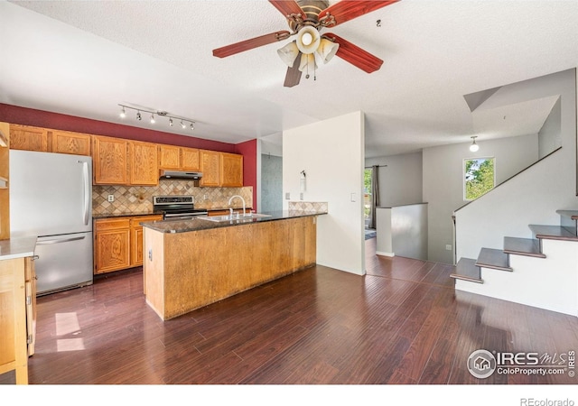 1305 Inverness Dr, Lafayette, CO 80026 - kitchen featuring stainless steel range with electric stovetop, freestanding refrigerator, under cabinet range hood, dark wood-style flooring, and a peninsula