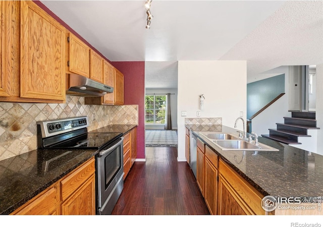 1305 Inverness Dr, Lafayette, CO 80026 - kitchen with stainless steel appliances, under cabinet range hood, dark wood-style flooring, backsplash, and dark stone countertops