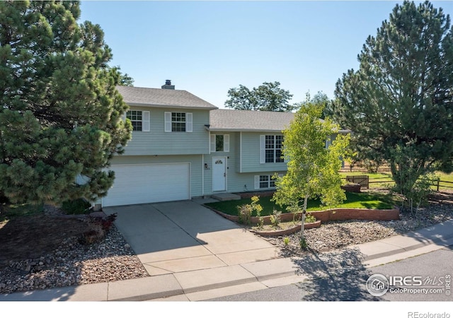1305 Inverness Dr, Lafayette, CO 80026 - split level home featuring a garage, concrete driveway, a chimney, and roof with shingles