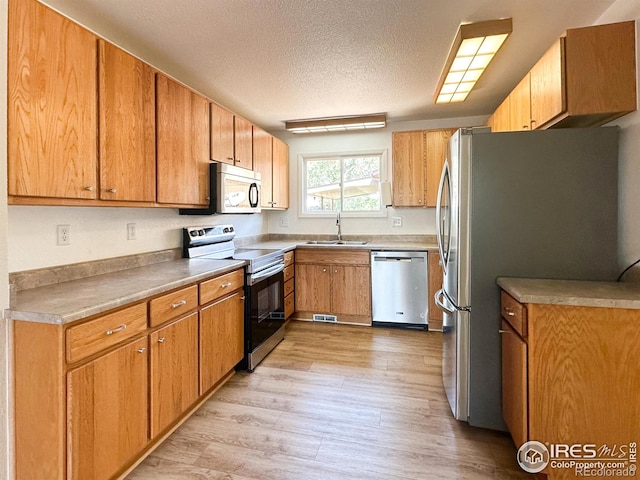 11941 S Clayson St, Parker, CO 80138 - kitchen featuring appliances with stainless steel finishes, light wood finished floors, a textured ceiling, and light countertops