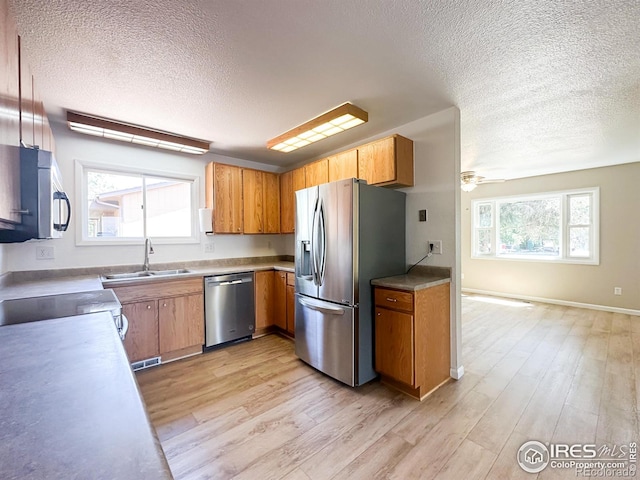 11941 S Clayson St, Parker, CO 80138 - kitchen featuring appliances with stainless steel finishes, a textured ceiling, light wood finished floors, brown cabinetry, and a ceiling fan