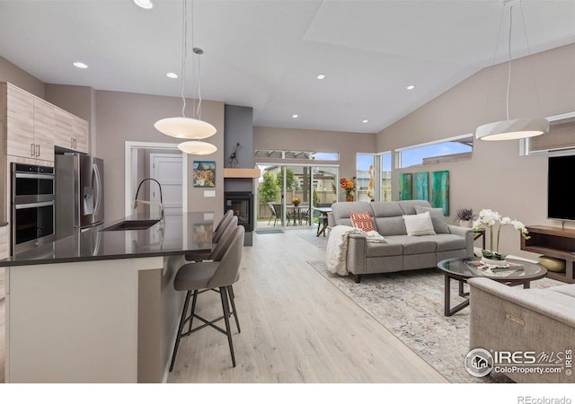 750 Kubat Ln Unit B, Longmont, CO 80503 - living room featuring light wood-style flooring, vaulted ceiling, recessed lighting, and a glass covered fireplace
