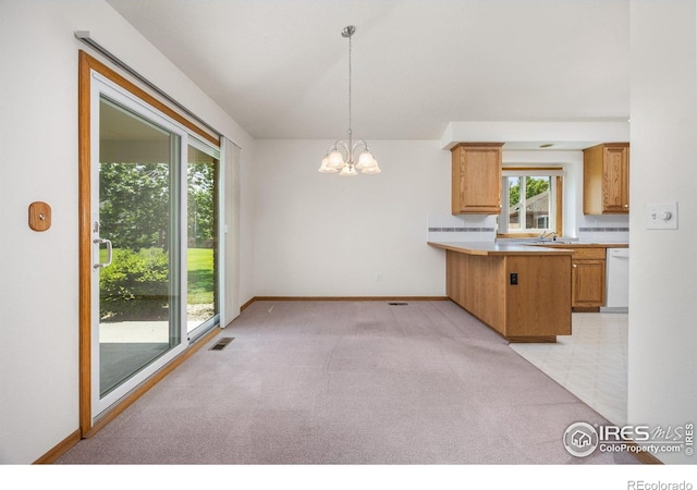1754 45th Ave, Greeley, CO 80634 - kitchen featuring white dishwasher, a chandelier, light colored carpet, a peninsula, and pendant lighting