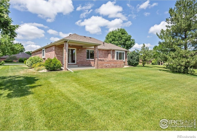 1754 45th Ave, Greeley, CO 80634 - rear view of house featuring brick siding, a yard, a patio area, and a shingled roof