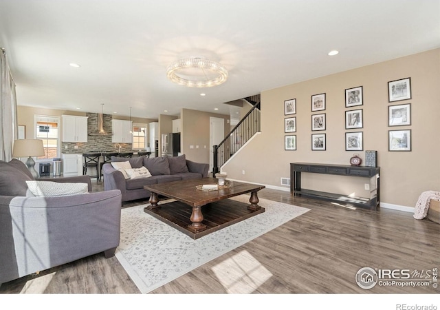 8541 Allenbrook Dr, Windsor, CO 80550 - living room with wood finished floors, a chandelier, stairs, and recessed lighting