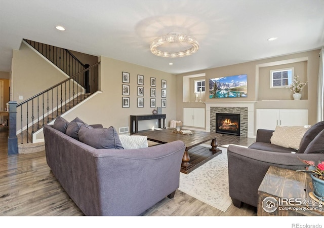 8541 Allenbrook Dr, Windsor, CO 80550 - living area featuring wood finished floors, a glass covered fireplace, stairway, and recessed lighting