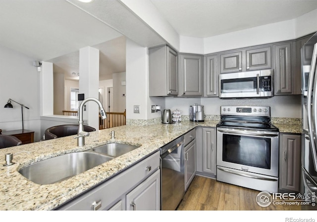 4644 W 112th Ct, Westminster, CO 80031 - kitchen featuring appliances with stainless steel finishes, gray cabinets, wood finished floors, and light stone countertops