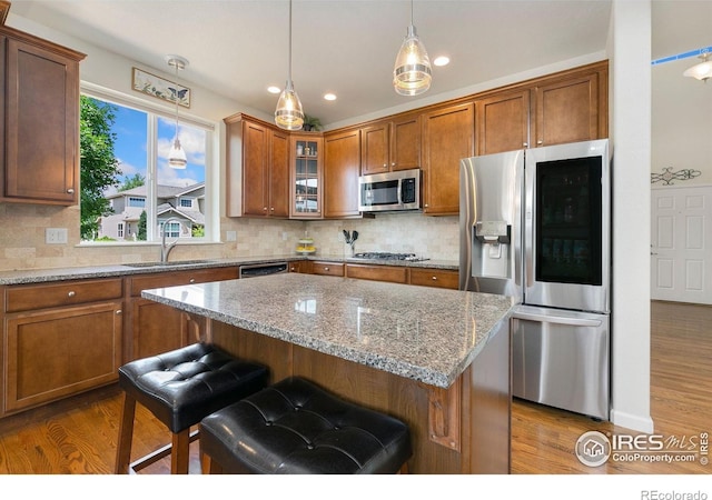 5355 Brookline Dr, Timnath, CO 80547 - kitchen featuring appliances with stainless steel finishes, brown cabinets, dark wood-style flooring, a breakfast bar, and glass insert cabinets