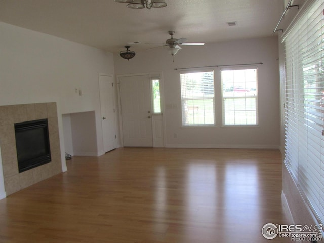1900 68th Ave Unit 701, Greeley, CO 80634 - unfurnished living room with light wood-style floors, a ceiling fan, plenty of natural light, and a tile fireplace