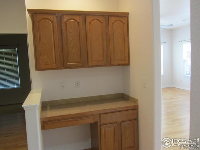 1900 68th Ave Unit 701, Greeley, CO 80634 - kitchen featuring built in desk, wood finished floors, brown cabinets, and light countertops