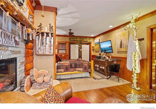 2238 Eagle Cliff Rd, Estes Park, CO 80517 - bedroom with hardwood / wood-style floors, crown molding, a wainscoted wall, and a stone fireplace