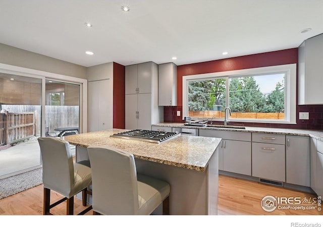 4655 Macky Way, Boulder, CO 80305 - kitchen featuring stainless steel gas cooktop, light wood-type flooring, gray cabinets, decorative backsplash, and a center island