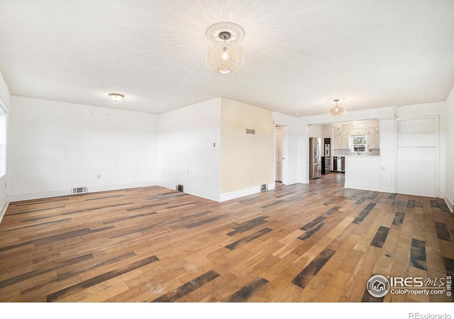 2118 N 47th Ave, Greeley, CO 80631 - unfurnished living room featuring wood finished floors and a chandelier