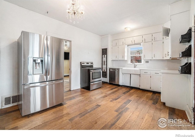 2118 N 47th Ave, Greeley, CO 80631 - kitchen with stainless steel appliances, light wood-style flooring, light countertops, white cabinetry, and a chandelier