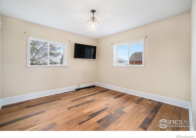 2118 N 47th Ave, Greeley, CO 80631 - empty room with hardwood / wood-style flooring, healthy amount of natural light, and a chandelier