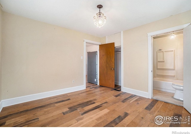 2118 N 47th Ave, Greeley, CO 80631 - unfurnished bedroom with light wood-style floors, a chandelier, and connected bathroom
