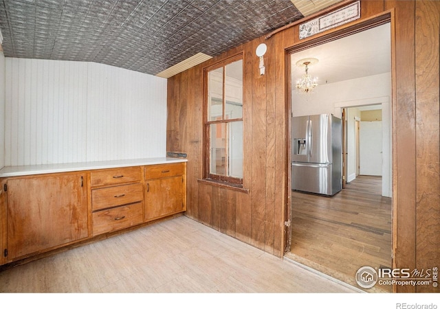 2118 N 47th Ave, Greeley, CO 80631 - kitchen featuring stainless steel fridge with ice dispenser, an ornate ceiling, wooden walls, a chandelier, and brown cabinets