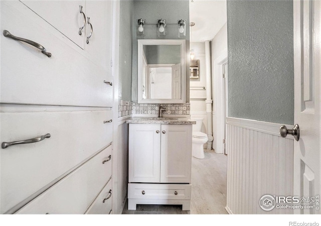2118 N 47th Ave, Greeley, CO 80631 - bathroom with vanity, a wainscoted wall, and wood finished floors