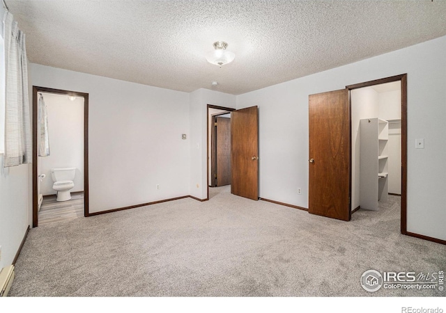 37416 County Road 45, Eaton, CO 80615 - unfurnished bedroom with carpet floors, a spacious closet, a textured ceiling, ensuite bathroom, and a closet
