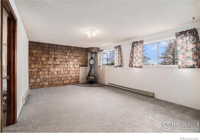 37416 County Road 45, Eaton, CO 80615 - spare room featuring a baseboard heating unit, carpet flooring, a textured ceiling, and a wood stove