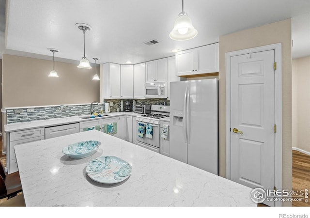 1703 Whitehall Dr Unit G, Longmont, CO 80504 - kitchen featuring white appliances, decorative backsplash, light stone counters, and white cabinetry
