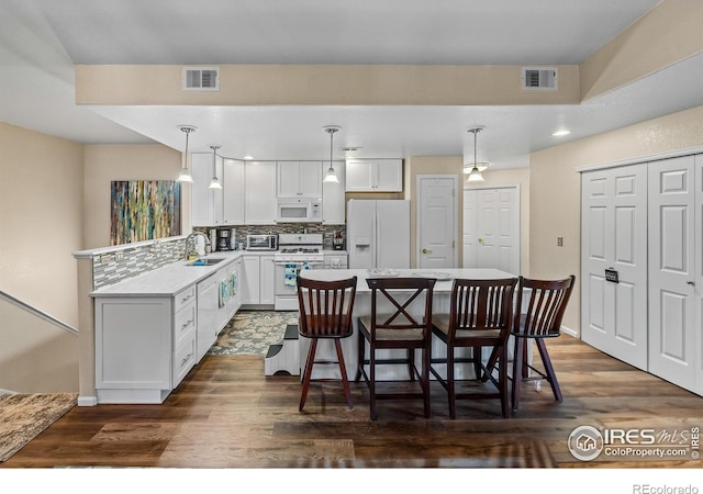 1703 Whitehall Dr Unit G, Longmont, CO 80504 - kitchen featuring white appliances, backsplash, light countertops, a center island, and white cabinets